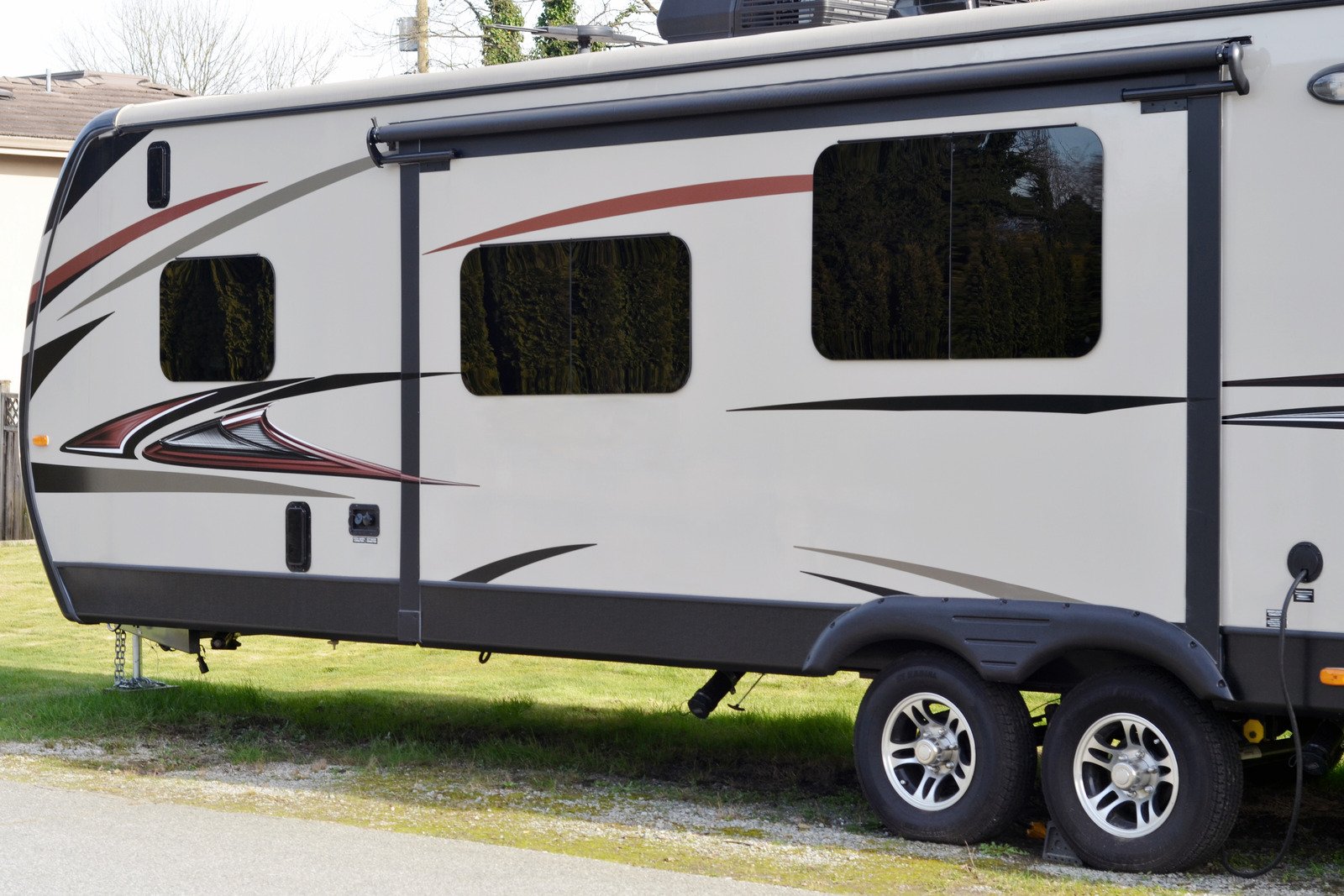 Closeup of a camping trailer on the side of a street in a residential neighbourhood.